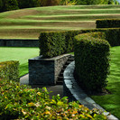 Curved steps and ramps amongst hedges lead to the tennis court.